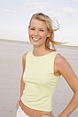 Jennifer Frau mit blonden Haaren, steht lachend an windigem Strand