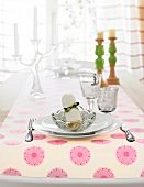 Table laid with glass plates, bowl and floral pattern tablecloth