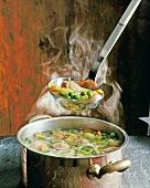 Hot pea stew with potatoes, leeks, carrots and sausage in casserole