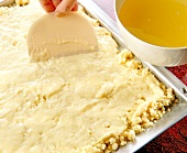 Pudding cream being spread on the dough in baking tray