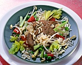 Rice salad with beef, peppers, peas and sprouts on plate