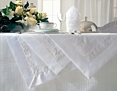 Laid table with white tablecloths, flowers, cup and saucer