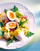 Halved and whole boiled eggs with vegetable ragout, ham and parsley on dish