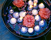 Blue and white floating lit candles with peony flowers in glass bowl