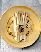 Asparagus with mustard cream sauce on yellow plate, overhead view