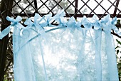 Vorhang aus transparenten Stoff als Windfang an einem  Ast oder Stange