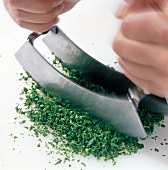 Close-up of herbs being minced with mezzaluna