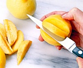 Close-up of woman's hands cutting slices of peaches with knife