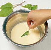 Leaf of journal being dipped in batter for preparing blossom in batter, step 2