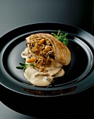Close-up of stuffed turkey breast fillet and light sauce in black dish