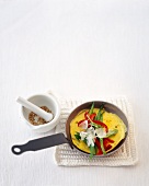 Vegetable omelette in pan with mortar on the side