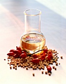 Glass jar with soya oil surrounded with soya beans and rose hips