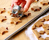 Close-up of woman's hand cutting cookies from the dough with cookie cutter