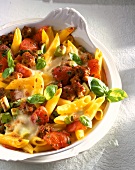 Close-up of penne pasta casserole with tomatoes, schweinmett, green onions and cheese