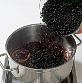 Hand pouring elderberries in pot, step 3