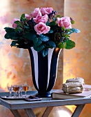Rosane Rosen in e. schwarzweiß ge- streiften Blumenvase auf einem Tisch