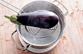 Eggplant on skimmer being put into pot with hot water