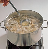 Skimming foam from chicken stock with ladle in pan, step 6