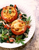 Close-up of stuffed tomatoes with spinach salad on plate