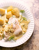 Close-up of cod fillet with mustard sauce, dill and potatoes on plate
