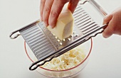 Appenzeller cheese being grated on kitchen grater in bowl