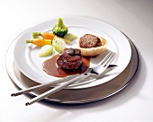 Tournedos and venison with vegetables on plate