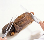 Roasted leg being carved with knife from bone, step 5