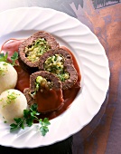 Close-up of stuffed beef with sauce, potato dumplings and parsley on plate