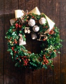 Close-up of Christmas wreath with white baubles and ribbons hanging on wood
