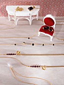 Close-up of gold necklace arranged on doll house chair and table