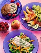 Sandwich, salad, fish fillet with vegetables, apple and berries in plates