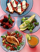 Chicken fillet with vegetables, orange juice, melon, berries and crisp bread on plate