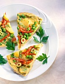 Close-up of potato omelette with peppers, olives, peas and parsley on plate