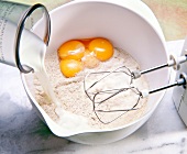 Pouring milk in bowl with egg yolk and flour for blending