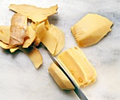 Close-up of kitchen knife cutting ginger into slices