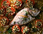 Close-up of sea bream with stuffed tomatoes, onions and rosemary