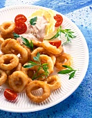 Close-up of squid rings with tomatoes and dip on plate