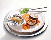 Pork with grilled tomatoes and baked potatoes on plate
