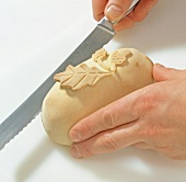 Close-up of hand cutting dough while preparing wild boar kidney, step 8