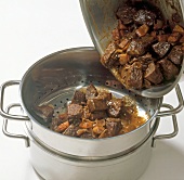 Close-up of pouring ragout while preparing venison stew, step 12