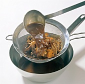 Sauce being removed through sieve for preparation of wild duck, step 7