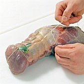 Close-up of hands binding venison for preparation of braised venison, step 6