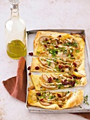 Pieces of pizza with brie, pear slices, cranberries in baking dish