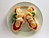 Croissant belegt mit Bananenscheiben und Erdbeerkonfitüre, close-up.