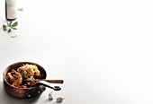 Roasted quail in saucepan and bottle of Merlot wine on white background, copy space