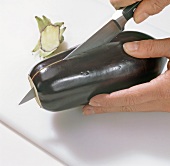 Close-up of hands cutting eggplant, step 2