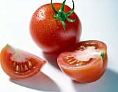 Close-up of whole and halved tomato on white background