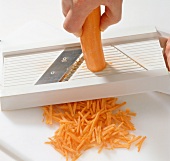 Close-up of carrot being sliced with plastic slicer, step 1