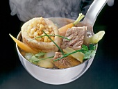Close-up of beef soup in ladle with vegetables and meat