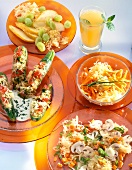 Various sauerkraut and asparagus salads on orange plate with glass of juice